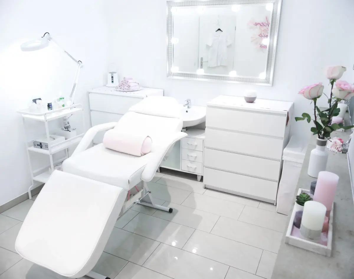 Behandlungsraum bei Glow Spot mit weißer Liege und beleuchtetem Spiegel