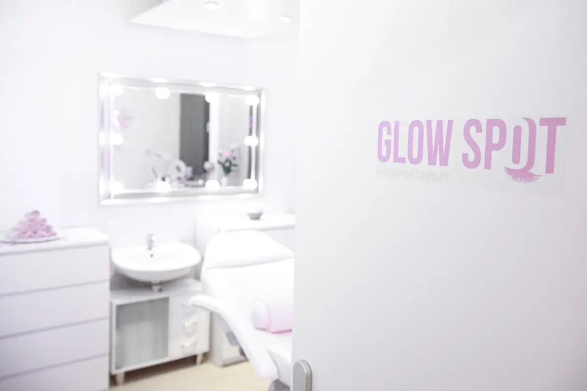 Blick in den Behandlungsraum mit Glow-Spot-Logo an der Tür